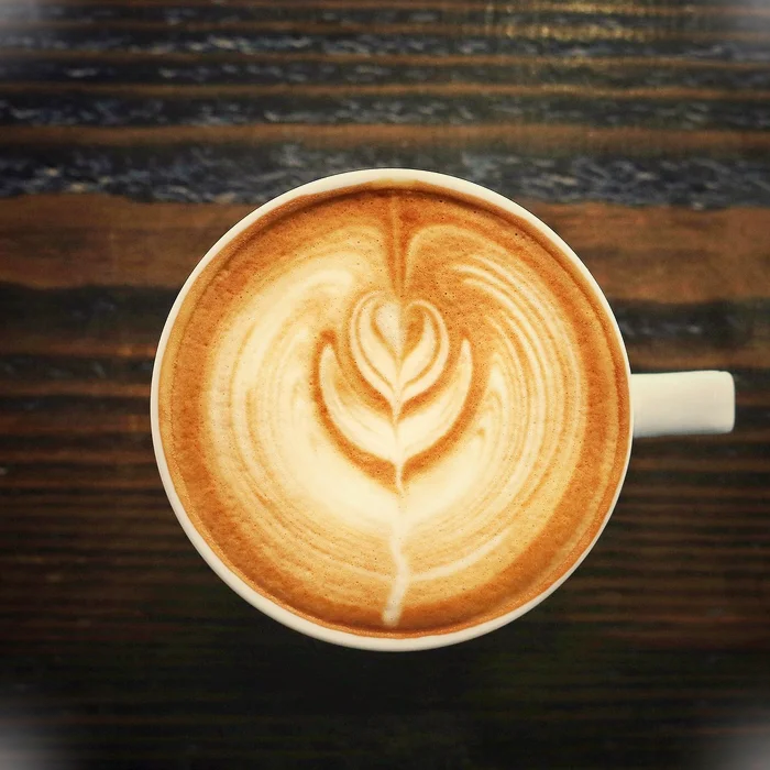 Steaming cup of coffee with coffee beans